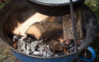 Kamp ateşi gündüz vakti odunları yakıyor, ateşte alevler içinde yanan odunları yakıyor. 