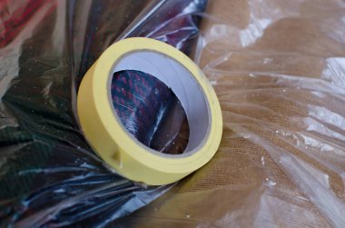 Sarı krep yapıştırıcı bant, boyada kullanılan maskeleme bandı yatakta aranmayan yerleri kapamak için şeffaf plastik folyoyla kaplı, kapat.