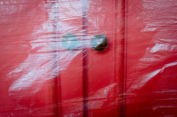 antique red colored wardrobe covered with transparent plastic foil, protection from dust and paint while decorating apartment