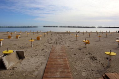 Issız yaya yolu ve sarı plajda güneş gözlüğü anlamına gelir. Yaz mevsiminden önce güneşli bir günde Rimini İtalya 'da boş plaj.