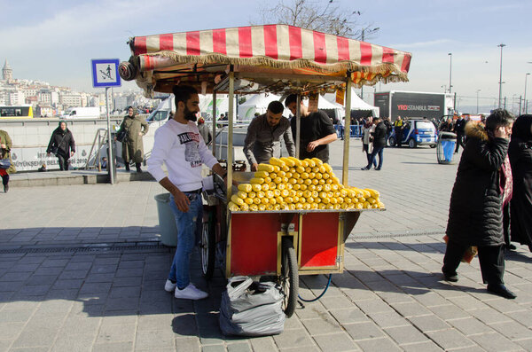 Istanbul, Turkey, March 07, 2019: street vendor by traditional street cart vending selling boiled and grilled corn outside of Egyptian Bazaar in Eminonu, streets of Istanbul with people passing by