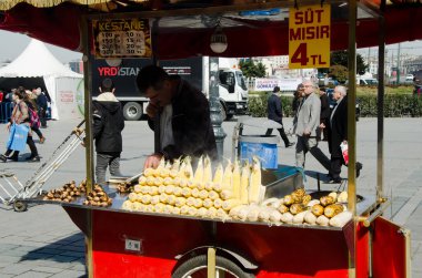 İstanbul, Türkiye, 07 Mart 2019: Eminonu, İstanbul 'da Mısır Pazarı önünde kestane ve haşlanmış mısır satan geleneksel sokak arabası satıcılarının arkasındaki sokak satıcısı