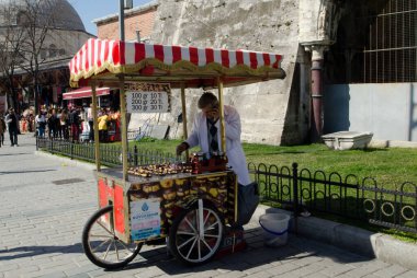 İstanbul, Türkiye, 08 Mart 2019: Geleneksel sokak yemeklerinde kestane satan sokak satıcısı, güneşli bir günde Ayasofya Meydanı, Sultahahmet Meydanı, İstanbul 'daki Ayasofya Müzesi' nin önünde kapanıyor