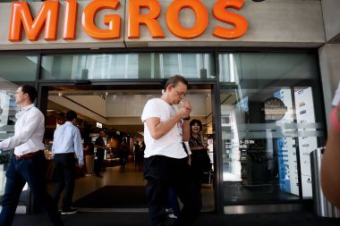 Zürih, İsviçre, 21 Temmuz 2019: Zürih 'te bir Migros restoranına giriş, restoranın önündeki insanlar, bir puroyu hafifletmek. 