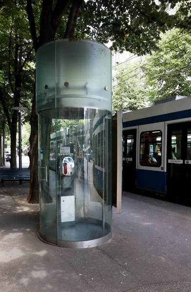 2019年7月19日 瑞士苏黎世 街上的空玻璃电话亭 四周环绕着树木和蓝色电车 — 图库照片