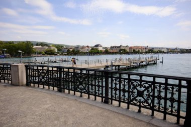 Zürih, İsviçre, 19 Temmuz 2019: Güneşli bir günde bulutlu mavi gökyüzü ve rıhtımda çok az insan olan Zürih Gölü 'nün bir kısmı. Zürih Gölü 'nün rıhtımı ve şehrin panoraması