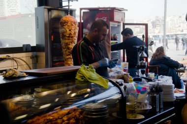 İstanbul, Türkiye, Mart 07.2019: Mısır Çarşısı yakınlarındaki bir restoranın içinde, tezgahta duran koruyucu eldivenli işçiler telefona bakıyorlar. Dönen dikey tükürükte donör kebabı, geleneksel yemek.