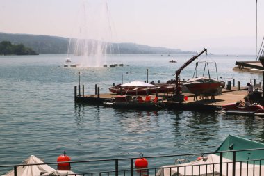 Zürih, İsviçre, 23 Temmuz 2019: Zürih Gölü 'nün arka planında bir boks maçı ve çeşmesi için liman.
