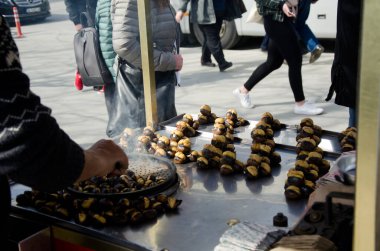 İstanbul, Türkiye, 07 Mart 2019: Eminonu, İstanbul 'da Mısır Çarşısı önünde kestane satan geleneksel sokak arabası satıcısının eli