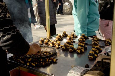 İstanbul, Türkiye, 07 Mart 2019: Eminonu, İstanbul 'da Mısır Çarşısı önünde kestane satan geleneksel sokak arabası satıcısının eli