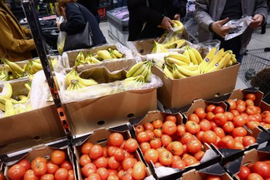 Nis, Sırbistan, 03 Şubat 2019: Müşteriler muzları satın almak ve Alman indirim zinciri süpermarketi Lidl 'de bir muz ve domates rafının önünde plastik poşete koymak için seçiyor.