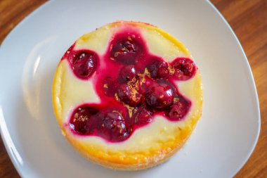 Tahta masadaki beyaz tabakta kirazlı cheesecake..