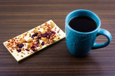 Mavi kupanın yanında kurutulmuş böğürtlen, meyve ve badem ile beyaz çikolata..