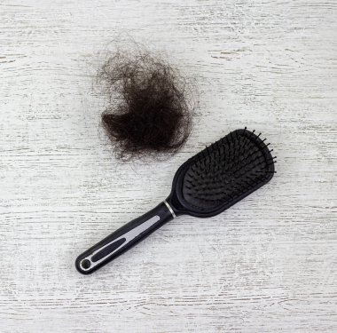 Bir kürek fırçası ve tahta bir arka planda bir tutam saç..