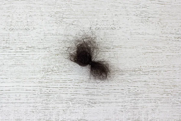 Il ciuffo di capelli neri su un pavimento di legno. — Foto Stock