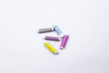 Beyaz arkaplanda renkli dikiş iplikleri.