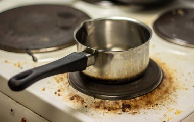 Kirli beyaz sobanın üstünde bir tencere.