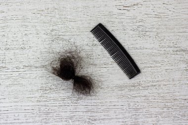 Tahta bir arka planda bir tarak ve bir tutam saç..