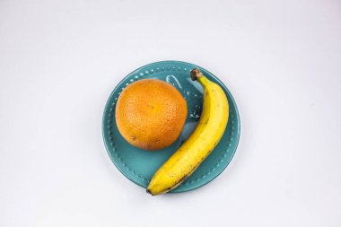 Turkuaz tabakta bir greyfurt ve bir muz..