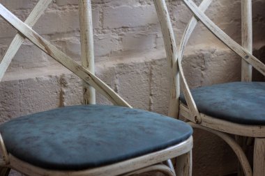 Beyaz tuğla duvarın arka planında yumuşak mavi koltuklu ahşap sandalyeler.