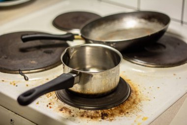 Kirli beyaz sobanın üstünde bir tencere ve bir tava..