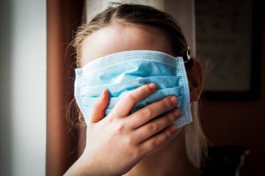 Tıbbi maske takmış güzel bir Avrupalı kız. Grip veya koronavirüs enfeksiyonundan korunmak için 7 yaşındaki bir kızın solunum cihazına bağlanması. Seçici odak