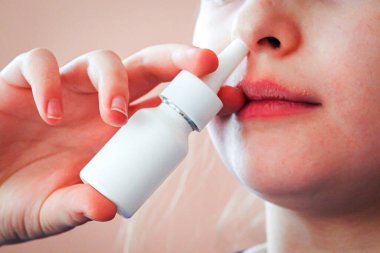 Kötü soğuk ve burnu akan burun spreyi kullanan küçük kız.