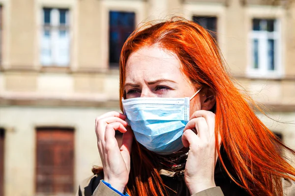 Hermosa joven europea con cabello de jengibre en la calle con una mascarilla médica —  Fotos de Stock