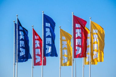 IKEA, IKEA mağazasında gökyüzüne karşı bayrak sallıyor. IKEA dünyanın en büyük mobilya perakendecisi ve mobilya montajına hazır satıyor.. 