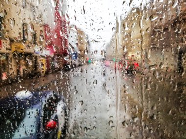 Yağmurlu bir tramvayın ıslak camındaki yağmur damlalarını, caddenin manzarasını ve yağmurlu bir günde trafiği kapatın.