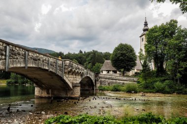 Eski Sv Kilisesi. Vaftizci Yahya ve Slovenya 'daki Bohinj Gölü kıyısında bir köprü.
