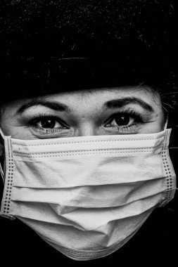 Güzel Avrupalı genç bir kadının siyah beyaz portresi. Covid19, Coronavirus 'a karşı koruyucu bir tıbbi maske takılı.