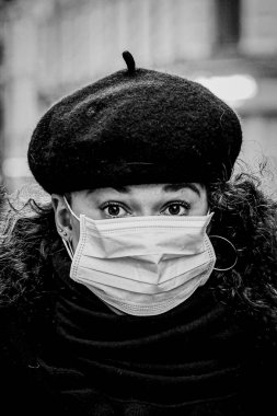 Güzel Avrupalı genç bir kadının siyah beyaz portresi. Covid19, Coronavirus 'a karşı koruyucu bir tıbbi maske takılı.