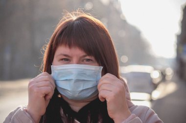 Tıbbi maskeli güzel bir Avrupalı kadın. Koronavirüsten korunmak için solunum cihazına bağlanmış bir kadın.