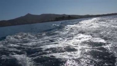 Hızlı bir teknenin gri suyu Denize yansıyan güneş ışınlarına karşı.