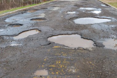 Bir sürü çukurla dolu asfalt bir yol, çukurlar suyla doludur..