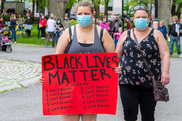 Saint John, NB, Kanada - 14 Haziran 2020: Siyahların Yaşamı Önemlidir rallisi. İki kadın maske takıyor, biri protesto işareti taşıyor..