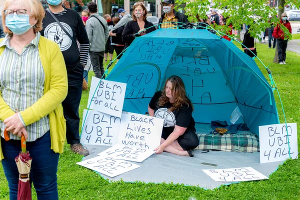 圣约翰 加拿大 2020年6月14日 黑人生命问题集会 一个女人坐在蓝色的帐篷里 周围都是标语 — 图库照片