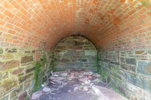 Inside an old ammunition storage magazine. It is made from brick and stone. It was built in the 1800s, but is empty now.