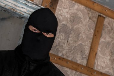 Terk edilmiş bir binada maske takan bir adam. O, izleyiciye bakıyor. Bir açıyla yakın görünüm.