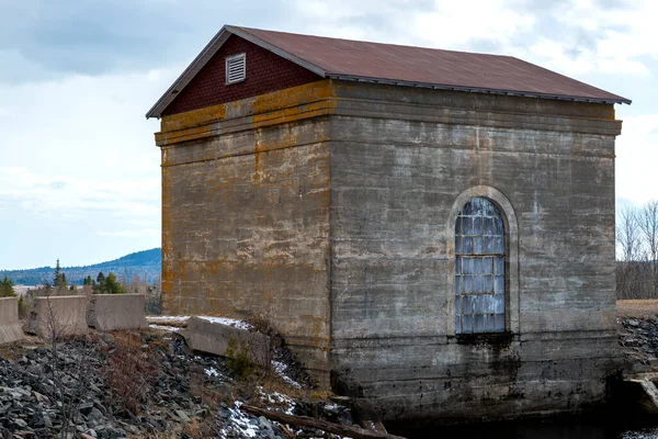 一个古老的水电站 苔藓生长在褪了色的混凝土表面上 拱形窗户面对水 车站已不再使用 — 图库照片