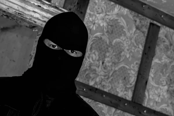 放棄された建物の中にマスク フードを身に着けている男 彼は視聴者を見つめている 角度でビューを閉じます 暗い黒と白の画像 — ストック写真
