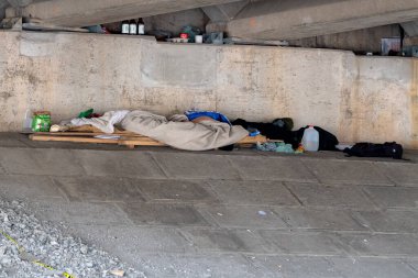 Saint John, NB, Kanada - 2 Haziran 2019 Evsiz bir insanın köprü altında yaşadığı yer. Derme çatma bir yatak, birkaç giysi ve diğer eşyalar var..