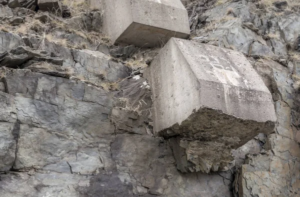 Concrete blocks on the side of a cliff. These blocks anchor the ends of rods used to reinforce the cliff to prevent it from colapsing.