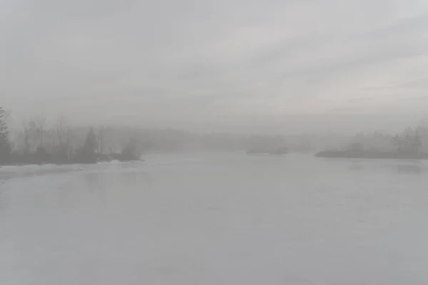 霧の日に凍った湖 湖は固体氷であり 空は曇っている 対岸には木々が見える コントラストの低い画像 本文室 — ストック写真