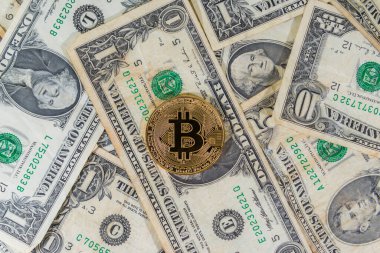 Biraz kirli Amerikan banknotları üzerinde altın bir bitcoin 'in yakın çekimi. Görüntü yukarıdan geliyor. Bitcoin genellikle bilgisayar dosyalarını şifreleyen bir virüs ve diğer yasadışı amaçlar için suçlulara isimsiz ödeme yapmak için kullanılır..