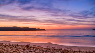 Avustralya, NSW 'nin merkez kıyısındaki Umina Sahili' ndeki Ocean Beach 'ten High Cloud ile pembe ve mor gün doğumu deniz manzarası.
