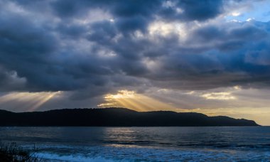 Ocean Beach, Umina, NSW, Avustralya 'dan Bulutlar Altında Güneş Işınları