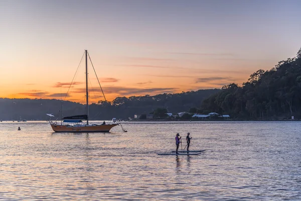Gündoğumu, Orta Sahildeki Ettalong Sahili, NSW, Avustralya 'daki Esplanade' den Paddleboders ve Boats.
