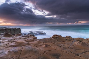 Tessellated Rock Platformu 'ndan Bulutlu Gün Doğumu Central Coast, NSW, Avustralya' daki North Avoca Sahili 'nde..